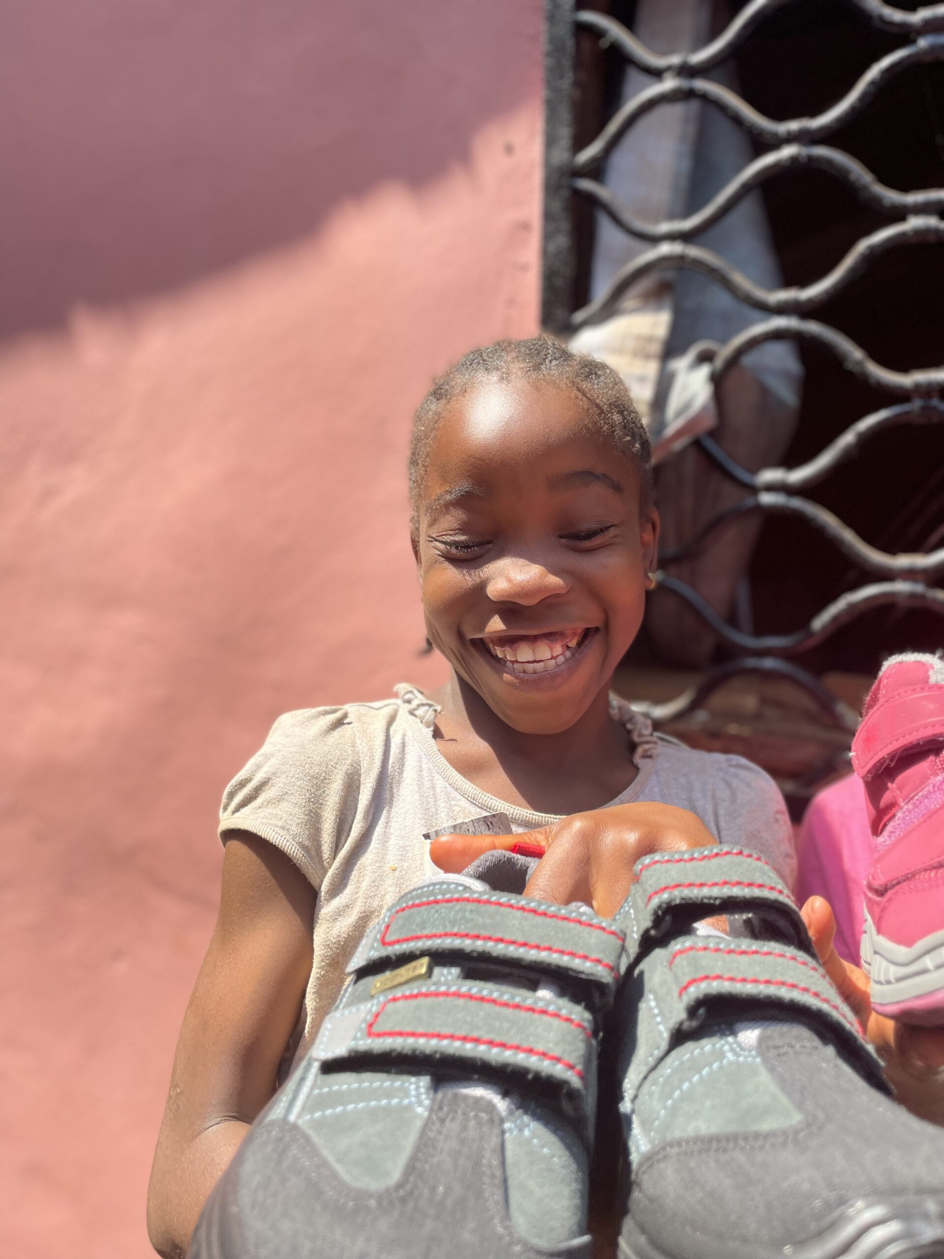 Eins unserer Waisenkinder freut sich riesig über die nagelneuen gespendeten  Schuhe